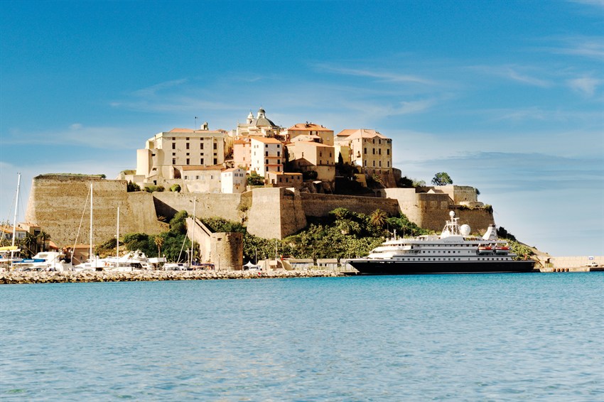 SeaDream yacht docked beneath a historic Mediterranean citadel